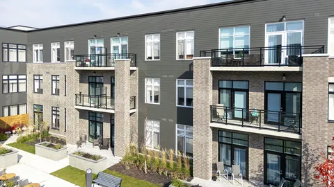 Residence facade with balconies and landscaped planting beds.