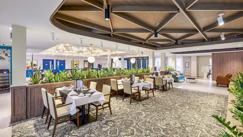 Dining tables with upholstered chairs and hanging lights.