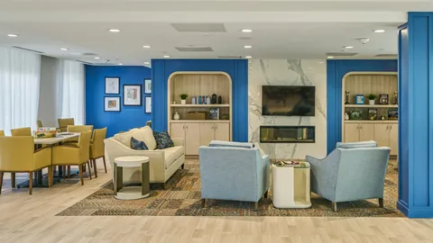 Lounge seating beside blue walls and large windows.