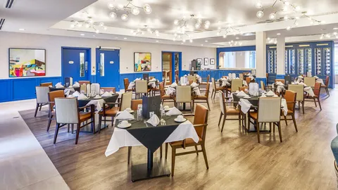 Dining room with set tables beside windows.