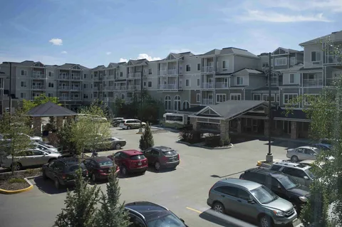 Four-storey residence with balconies and a covered entrance beyond the parking area