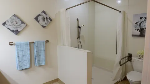 Bathroom with a walk-in shower, grab bars and blue towels