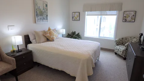 Bedroom with a double bed, armchair, lamps and framed floral artwork