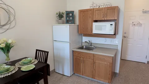 Kitchenette with a refrigerator, microwave, sink and a small dining table