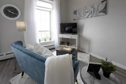 Sitting area with a blue loveseat, a television, a white cabinet and a flower print