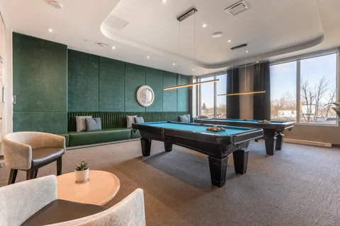 Two billiards tables beside a green wall and large windows