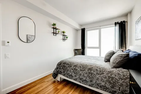 Bedroom with a patterned bedspread, mirror and glass balcony door