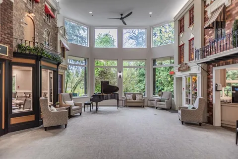 Tall lobby with a grand piano, armchairs and decorative storefront facades