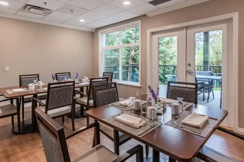 Dining tables with place settings beside windows and patio doors