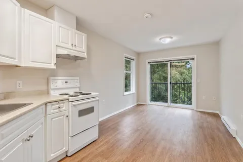 Empty room with a white kitchen and sliding balcony doors