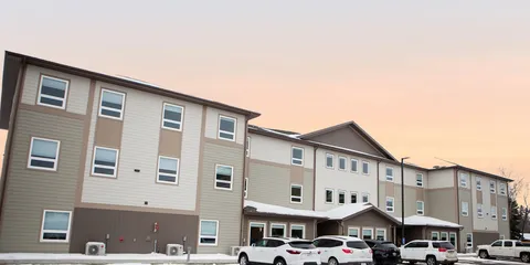 Residence exterior with windows, covered entrances and parked vehicles.