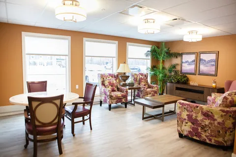 Sitting room with armchairs, tables and large windows.