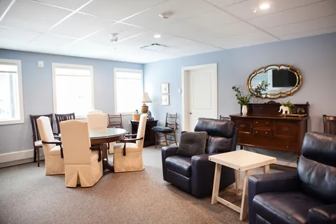 Lounge with armchairs, a round table and a wooden cabinet.