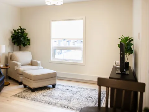 Suite sitting area with a chair, ottoman and window.