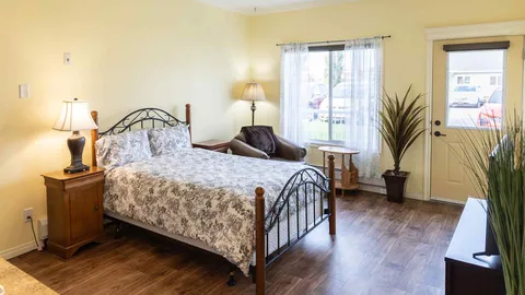 Bedroom with a metal-framed bed, floral bedding, bedside lamps and an armchair