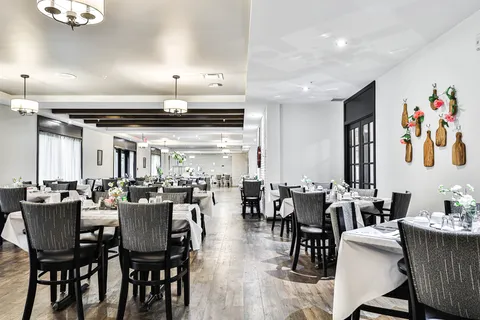 Dining room with set tables, dark chairs and wall decorations