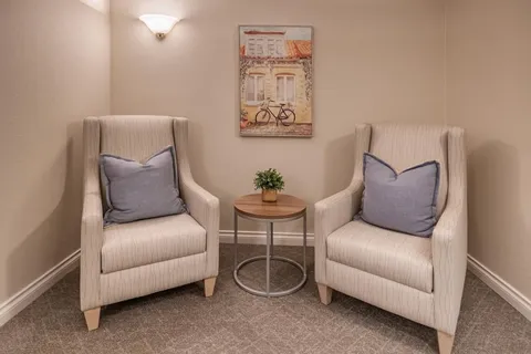 Two armchairs beside a round table under a bicycle painting