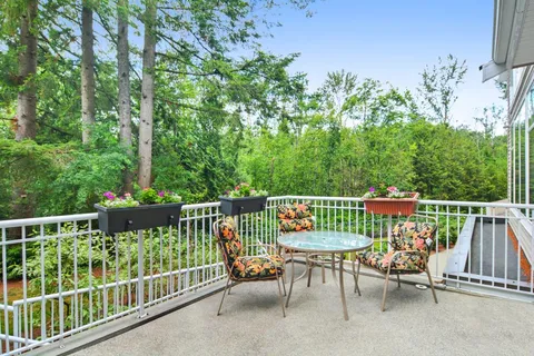 Balcony with a glass table, three chairs and flower planters