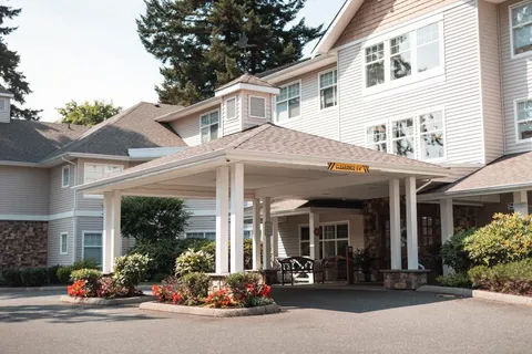 Residence entrance with a covered driveway and landscaped flower beds