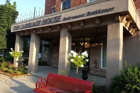 Covered residence entrance with flower planters and a red bench