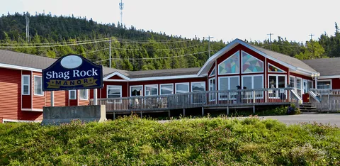 Red residence building with a glazed front wall, deck and entrance sign.