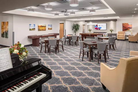 Room with tables, chairs, a piano and a television