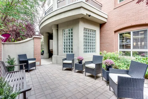Brick building beside a paved seating area with wicker chairs