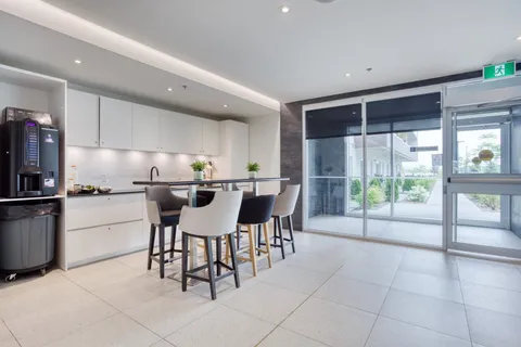 Shared kitchen counter with bar stools beside large windows.