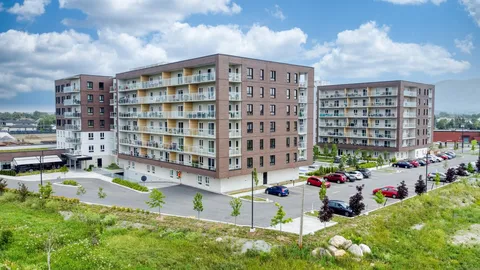 Residence balconies and parking area seen from a grassy bank.