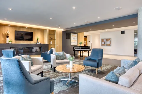 Lounge with blue armchairs, sofas, a fireplace and piano.