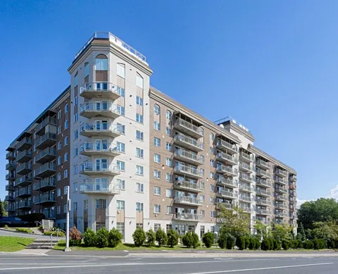 Multi-storey residence with balconies and a corner tower beside a road
