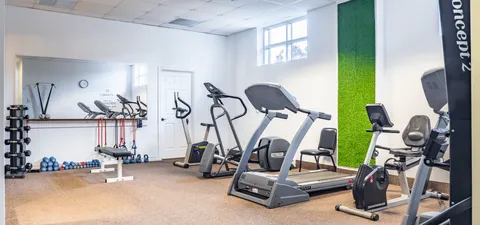 Exercise room with treadmills, bikes, weights and a wall mirror