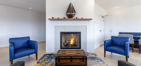 Blue armchairs beside a fireplace with a model sailboat above it