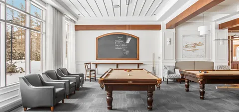Billiards room with two pool tables, armchairs and large windows