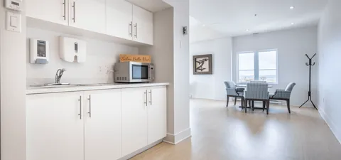 White kitchenette opening to a table with four upholstered chairs