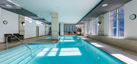 Indoor pool with entry steps, tiled columns and tall windows