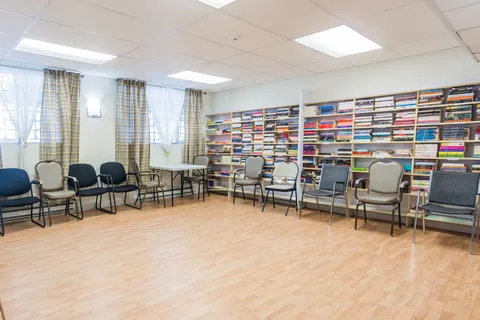 Library room with bookshelves, chairs and wooden flooring.