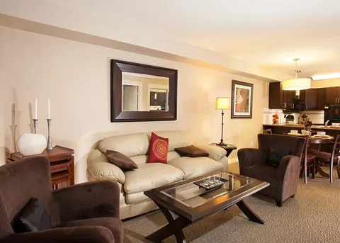 Suite living area with a sofa and armchairs beside a kitchenette.