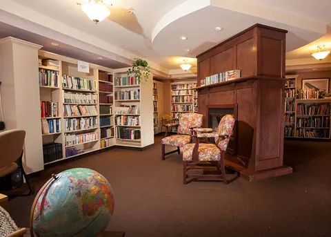 Library with bookshelves, armchairs and a globe.