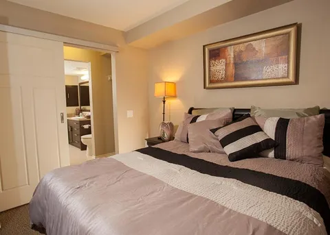 Suite bedroom with a double bed beneath framed artwork.