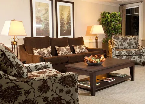 Lounge with a sofa, armchairs and lamps beside a window.