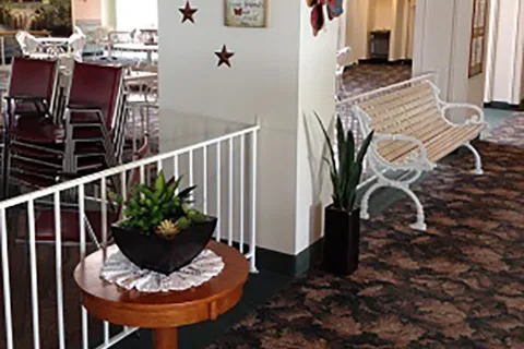 Lounge beside a dining room with a bench, railing and a potted plant.