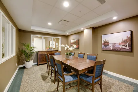 Dining table with blue chairs, a sideboard and framed landscape pictures