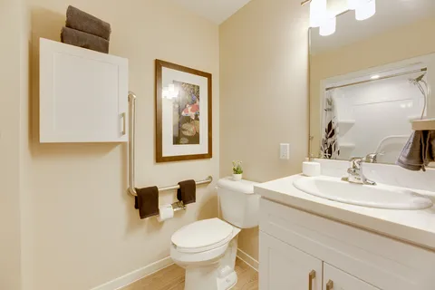 Bathroom with a sink, toilet and mirror reflecting a shower