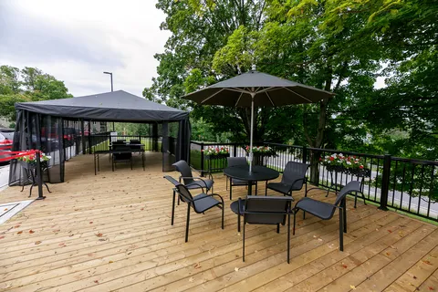 Wooden terrace with tables, chairs, umbrellas and a screened gazebo