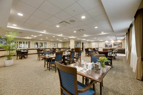 Dining room with blue chairs and tables set beside windows