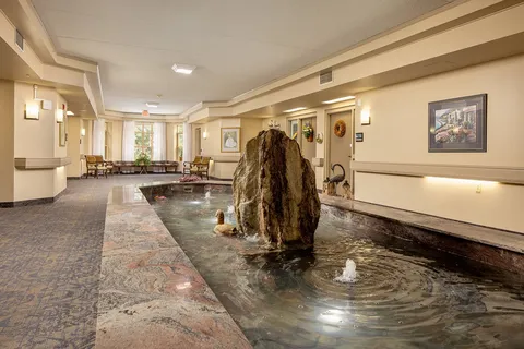 Indoor fountain and stone feature beside a seating area.