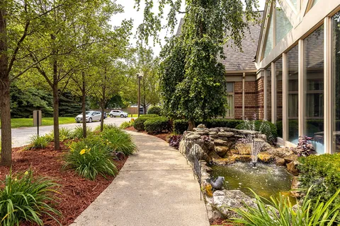 Walking path beside a lawn and rock fountain.