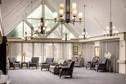 Atrium lounge with upholstered chairs and a vaulted glazed roof.