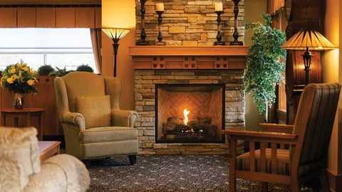 Fireplace seating area with armchairs and table lamps.